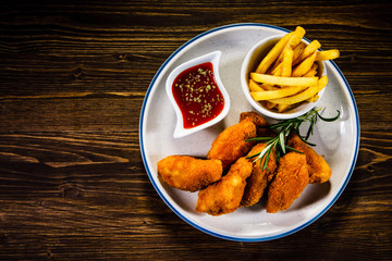 Chicken nuggets with french fries on wooden table 