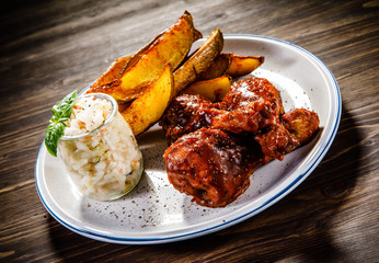 Barbecued chicken drumsticks with chips and vegetables 
