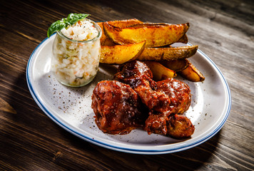Barbecued chicken drumsticks with chips and vegetables 