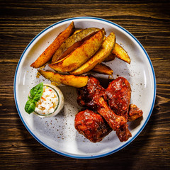 Barbecued chicken drumsticks with chips and vegetables 