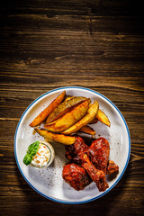 Barbecued chicken drumsticks with chips and vegetables 
