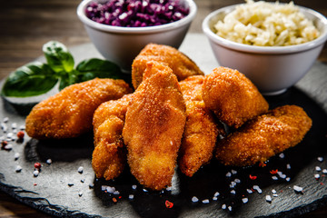 Fried chicken nuggets with cabbage served on black stone on wooden table