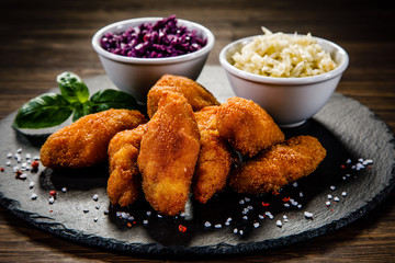 Fried chicken nuggets with cabbage served on black stone on wooden table