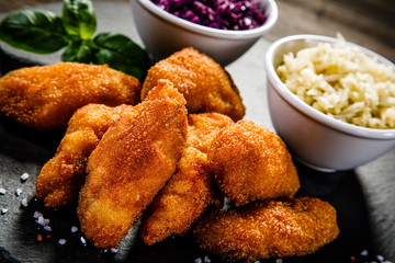 Fried chicken nuggets with cabbage served on black stone on wooden table