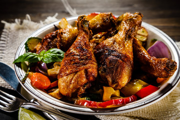 Roast chicken drumsticks on wooden background