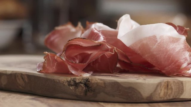 Slow motion prosciutto falling on wood board