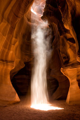 A photo of one of the spectacular light beams in Upper Antelope Canyon located in Page, Arizona. A long exposure of sand falling through the beam gives it an unusual waterfall look through the light.