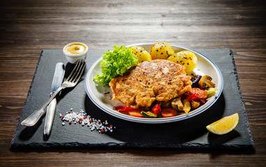 Fried pork chop with potatoes served on black stone