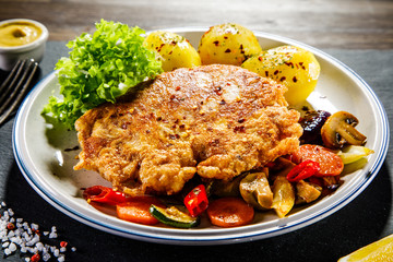 Fried pork chop with potatoes served on black stone