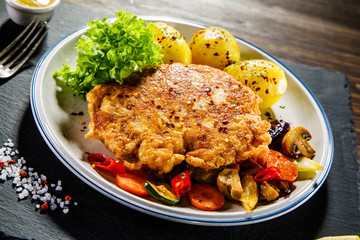 Fried pork chop with potatoes served on black stone