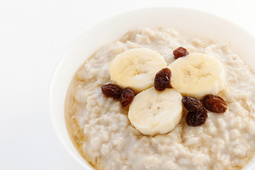Oatmeal with raisins and banana on a white bowl. Diet. Diabetes Low GI. Healthy Porridge. Breakfast. Home cooking. Food. Vegetarian eating.