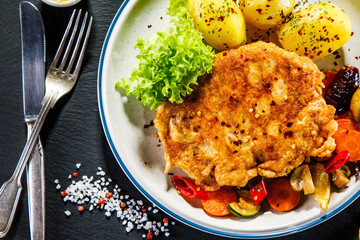 Fried pork chop with potatoes served on black stone