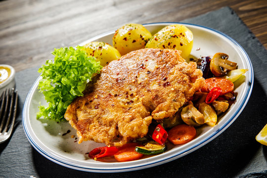 Fried pork chop with potatoes served on black stone