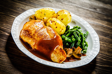 Grilled chicken fillet and vegetables on wooden table