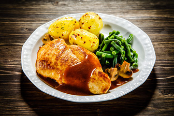 Grilled chicken fillet and vegetables on wooden table