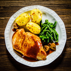 Grilled chicken fillet and vegetables on wooden table