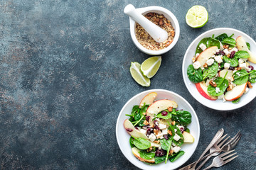 salad bowl of spinach, apple, soft cheese, nuts and cranberry. top view, healthy diet eating, superfood