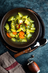 plate of fresh hot vegetable soup with broccoli, potato, green peas, onion and carrot. healthy vegan diet food, top view