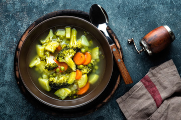 plate of fresh hot vegetable soup with broccoli, potato, green peas, onion and carrot. healthy vegan diet food, top view