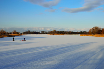 Wędkarze na zamarzniętym jeziorze łowią ryby pod lodem. © W Korczewski