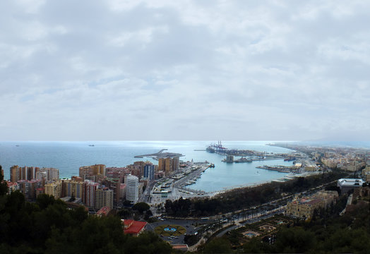panoramic aerial image of malaga in spain showing the coast with port and docks with surrounding city hotels and ships out at sea