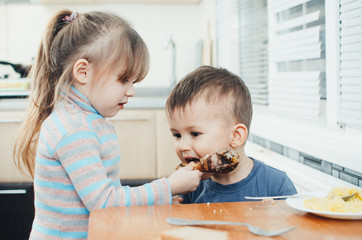 Children in the kitchen eat meat and mashed potatoes, very fun, share and feed each other