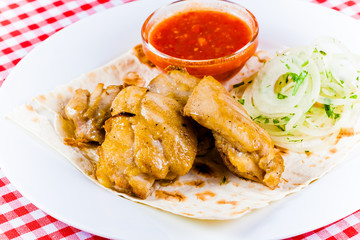 Grilled chicken with tomato sauce,onion, pita bread on white plate