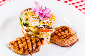 Grilled meat and vegetable salad on white plate