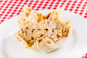 Beef stroganoff with sour cream in pita bread on white plate