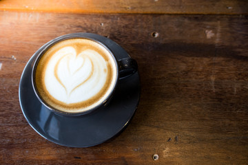 Coffee cup with latte art on the wooden table.