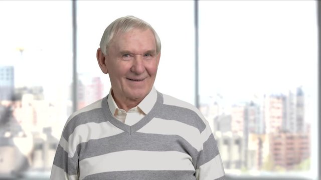 Elderly man looking being cautious. Senior man looking suspicious, window city background.