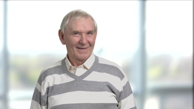 Older man with a suspicious or skeptical expression. Senior man with distrusting or disagreement look, blurred background. Human facial expressions and body language.