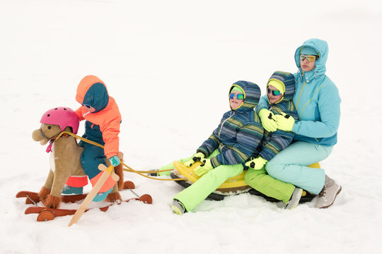 A happy mother with kids in sunglasses and a bright blue ski suit. Mother and children are happy together. A sports family on a snow-covered river with snow. Boys are very happy to play outdoors