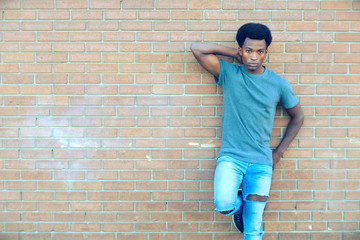 Fototapeta na wymiar young man standing posing brick wall outside cool attitude city lifestyle
