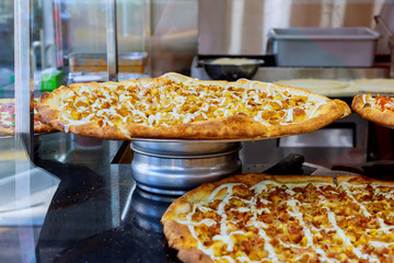 Pizza pies on display for sale in pizzeria. Selective focus.