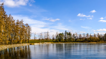 Frozen pond by trees in Uhrineves, part of Prague