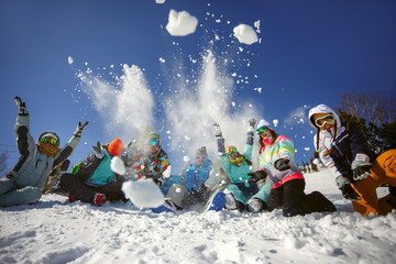 A group of friends of skiers and snowboarders fun throwing snow on top of the mountain.