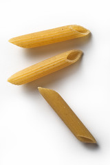 Three pieces of Penne wholemeal pasta isolated on white background