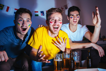 Exited sport fans watching match at home, friends having fun