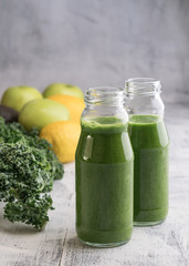 Healthy smoothie with kale in bottles on table