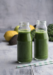 Healthy smoothie with kale in bottles on table