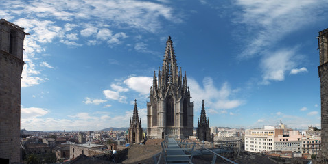 panoramic view of the city from barcelona cathedral roof with the gothic tower and blue sky
