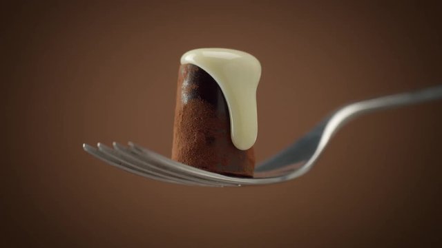 one chocolate candy on fork covered by white cream, slowly falling down