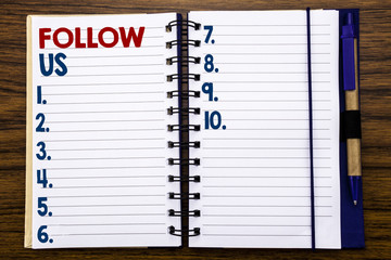 Writing text showing Follow Us. Business concept for Social Media Marketing Written on notebook note paper, wooden background with pen and marker.