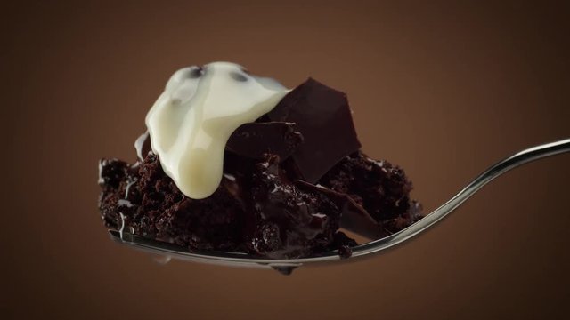 piece of chocolate cake on fork with slowly moving drops of white cream on it. macro slowmotion clip of chocolate cake
