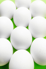 Symmetry of white eggs on bright light green background.