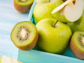 Green apples and kiwi on turquoise background