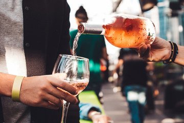 People have fun and drink cocktails. The waiter pours wine into a glass.