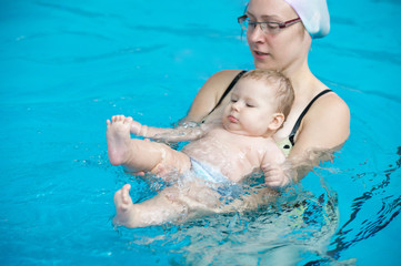 Mother teaching baby to swim in water pool
