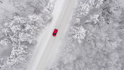 red car driving on a snow covered road, aerial view